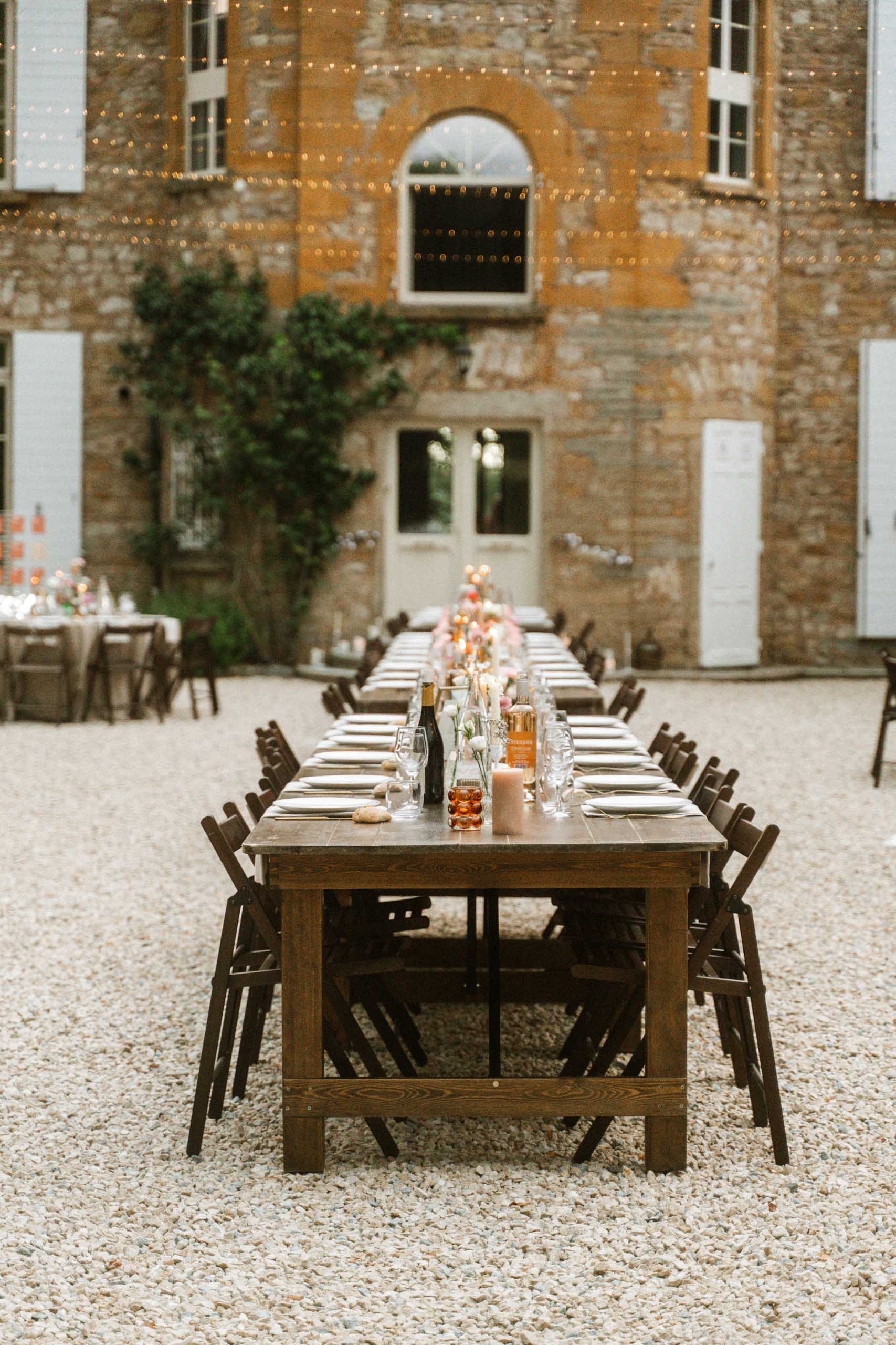 Vidéaste mariage beaujolais. Une longue table rectangle dans la cour intérieur d'un manoir.une table très bien dressée pour accueillir une réception de mariage.